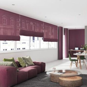 Helles Wohnzimmer mit weinroten und grünen Akzenten und weinroten Faltrollos