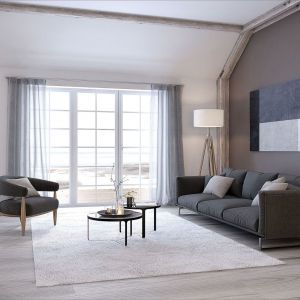 Helles lichtdurchflutetes Wohnzimmer mit dunklen modernen Möbeln und hellgrauen transparenten Vorhängen