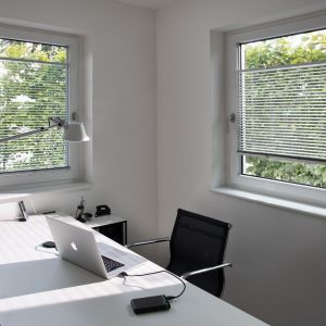 Ein Homeoffice mit einem Laptop auf einem Schreibtisch, umgeben von Büromaterialien und einer gemütlichen Atmosphäre.